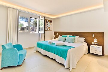 A bedroom with a large bed and a blue chair