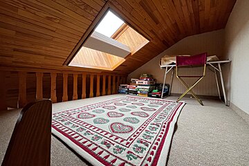 A room with a rug and a stack of board games including scrabble