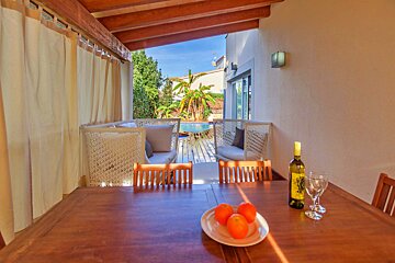 A bottle of wine sits on a table next to a plate of oranges