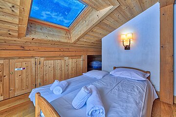 A bedroom with a bed and a skylight above it