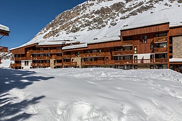 A snowy building with a balcony and a mountain in the background