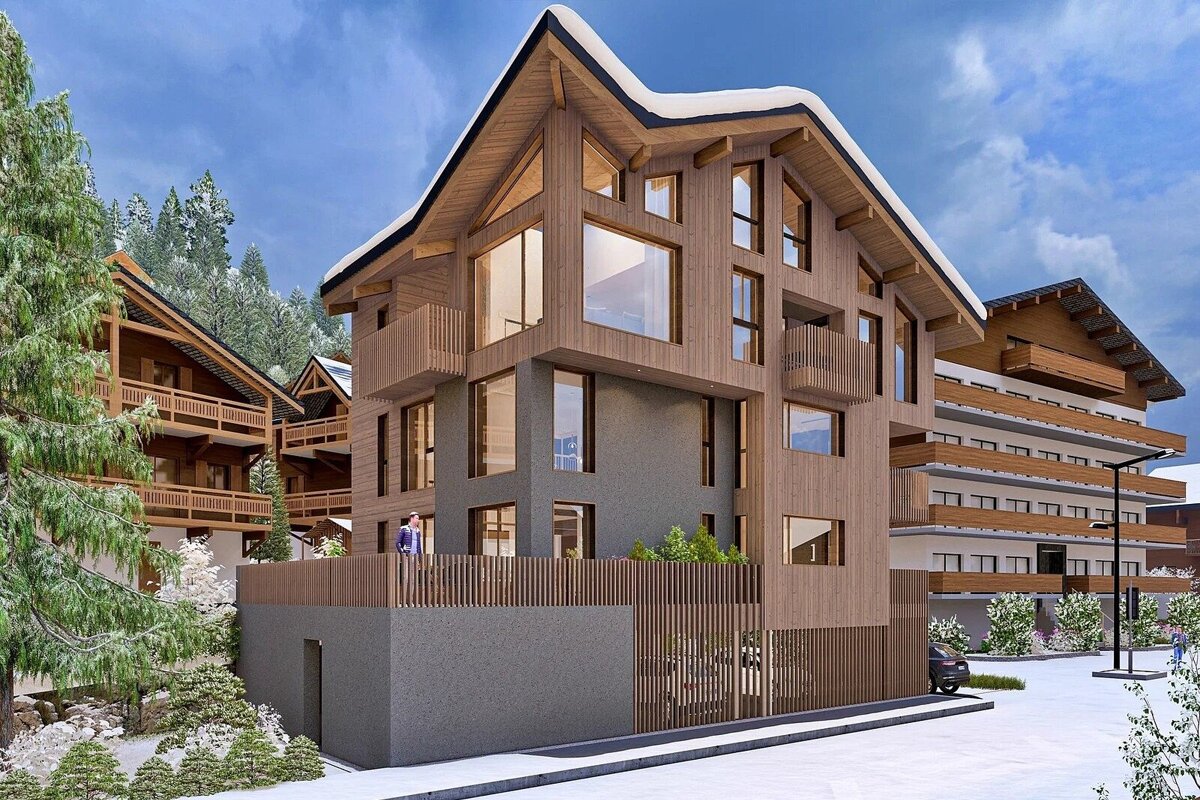 Modern wooden chalets and apartment buildings with large windows and balconies in a snowy mountain setting, surrounded by evergreen trees.