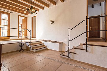 A hallway with stairs and a chandelier hanging from the ceiling
