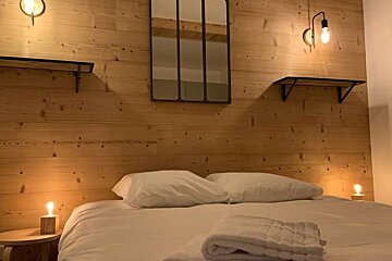 A bedroom with a bed and a mirror on the wall