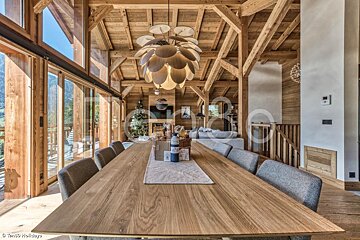 A large wooden table with a chandelier hanging from the ceiling