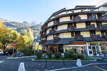 A bicycle is parked in front of a building with mountains in the background