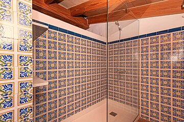 A shower with blue and white tiles on the wall