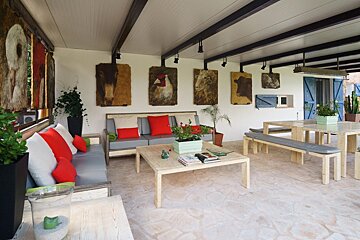 A living room with a couch a table and paintings on the wall