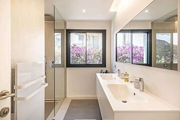 A bathroom with two sinks and a window with purple flowers