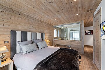 A bedroom with a bed and a television on the wall