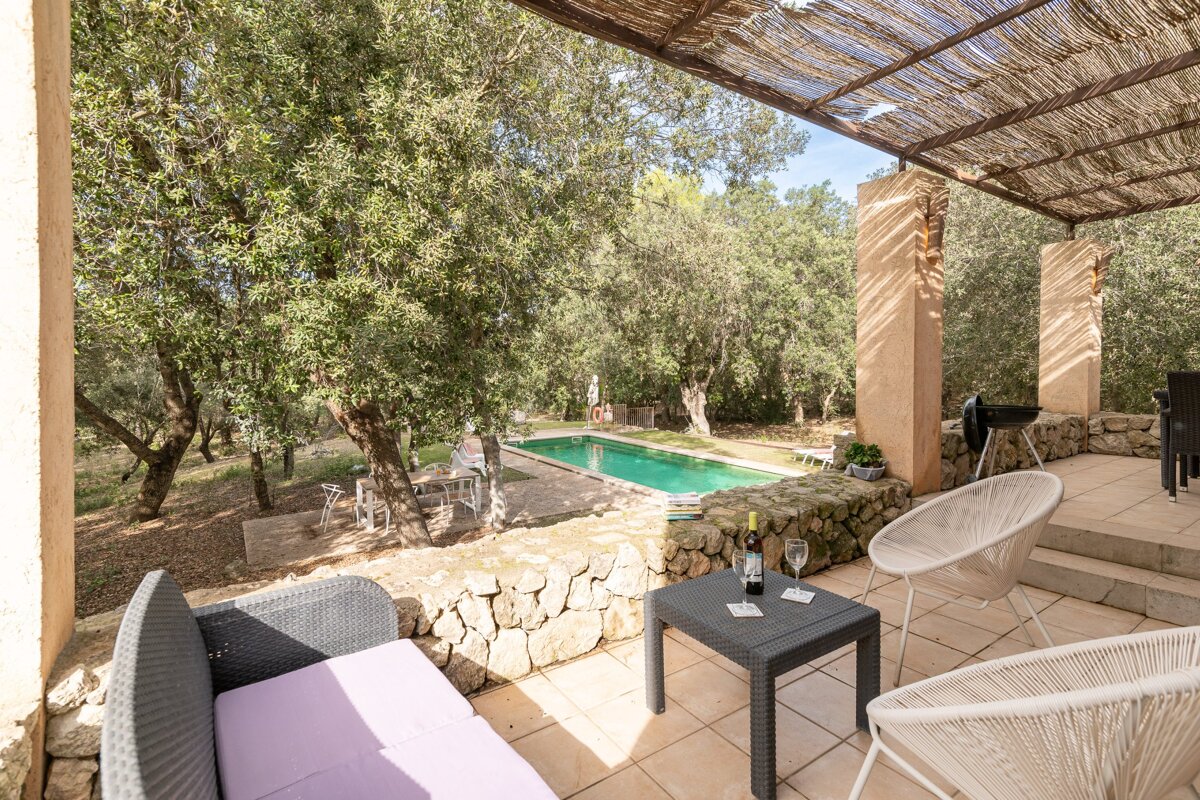 A patio with chairs and a table with a bottle of wine on it