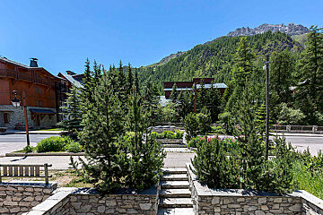 A stone wall with stairs leading up to a building with a mountain in the background