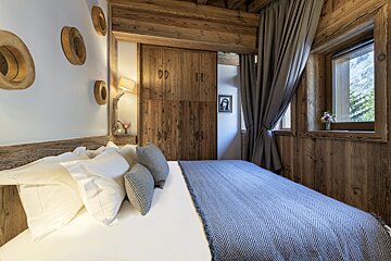 A bedroom with a bed and a window with a picture of a woman on the wall