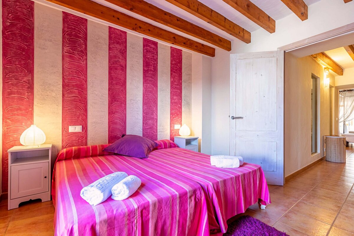A bedroom with pink and white stripes on the wall