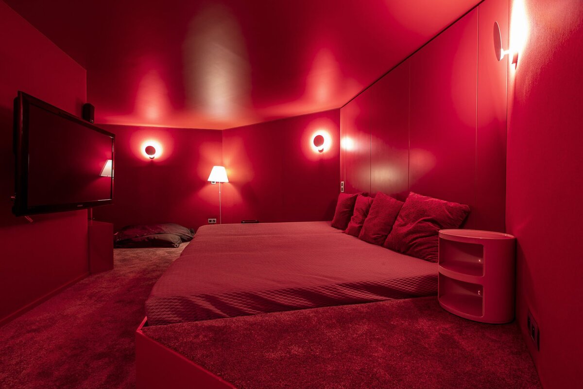 A bedroom with red walls and a flat screen tv