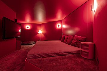 A bedroom with red walls and a flat screen tv