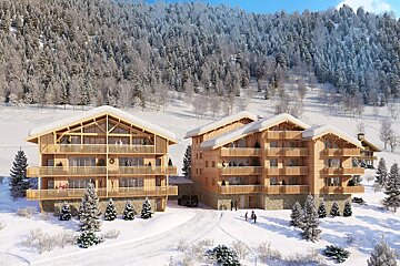 Two modern wooden chalets, snow-covered, nestled in a winter mountain landscape with a dense forest backdrop under a blue sky.