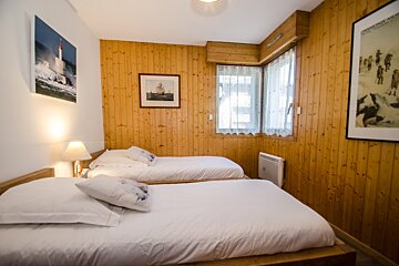 A bedroom with two beds and a picture of a boat on the wall