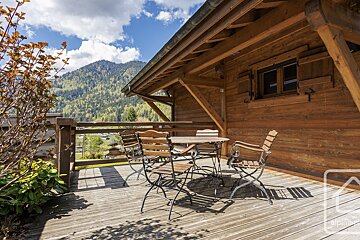 A wooden cabin with a table and chairs on the deck