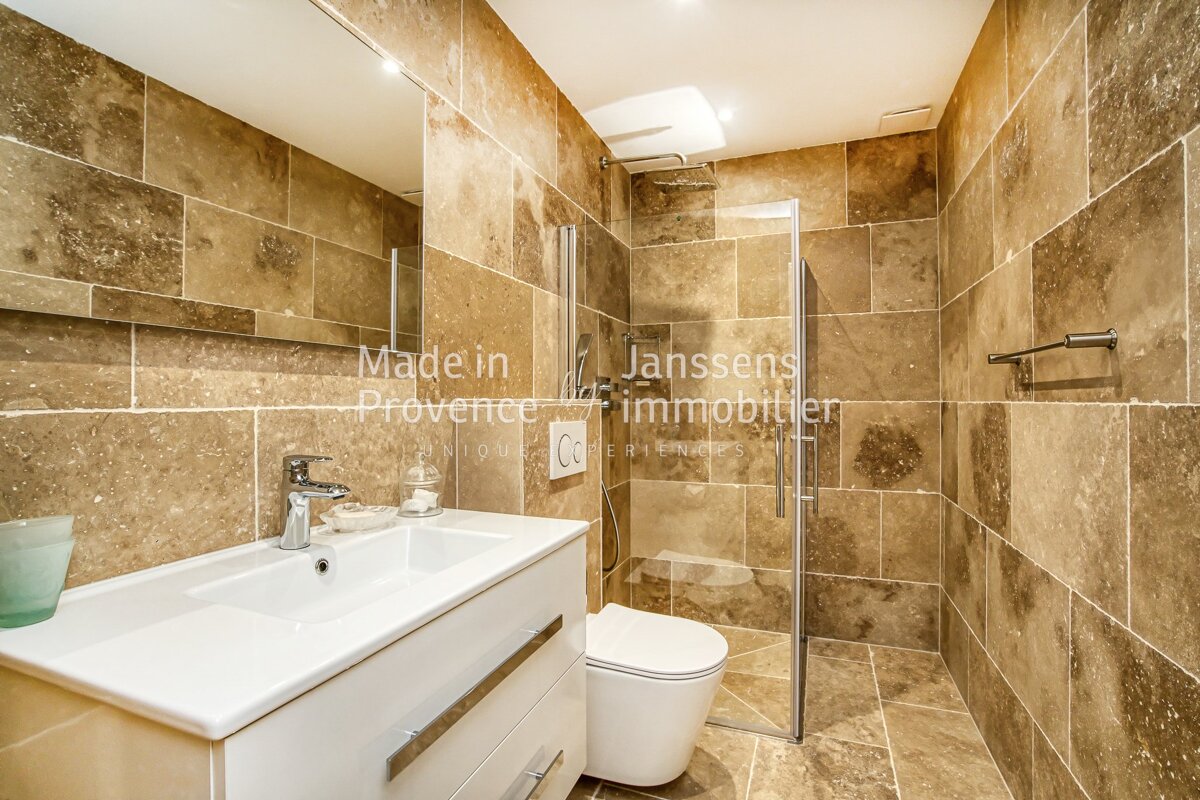 A bathroom with brown tiles and the words made in janssens immobilier