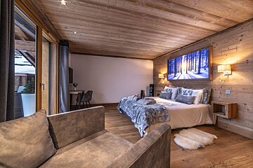 A bedroom with a large bed and a chair