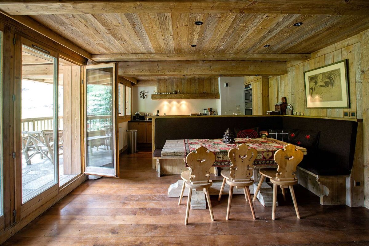 A wooden dining room with a table and chairs