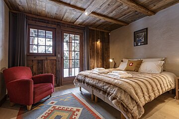A bedroom with a large bed and a red chair