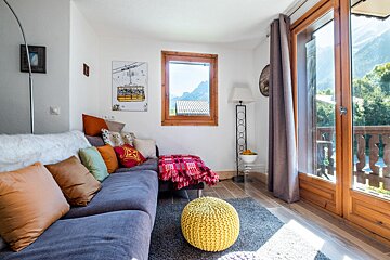 A living room with a couch and a yellow ottoman