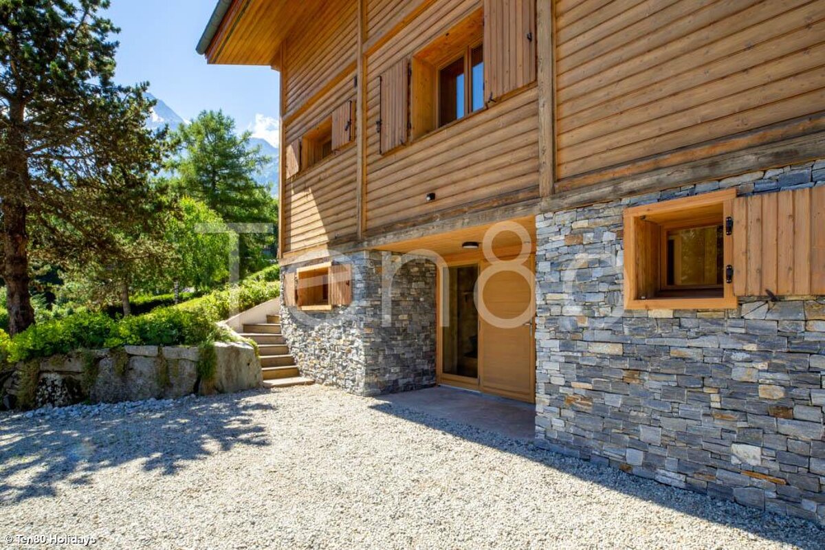 A wooden house with a stone wall has the number 8 on the side