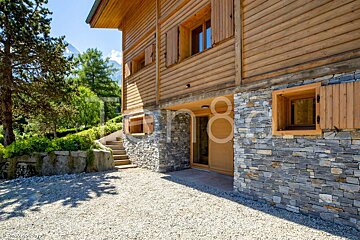 A wooden house with a stone wall has the number 8 on the side