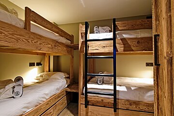 A bunk bed with a ladder and slippers on it