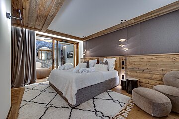 A bedroom with a large bed and a chair
