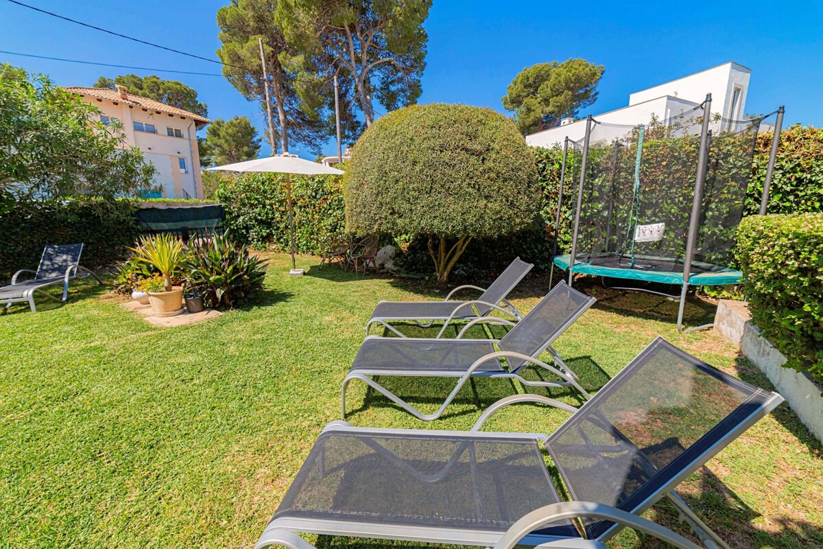 A trampoline in a backyard with lawn chairs