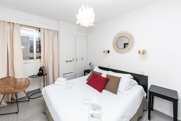 A bedroom with a large bed and a mirror on the wall