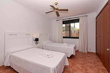 A bedroom with two beds and a ceiling fan