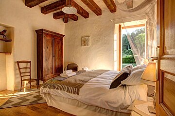 A bedroom with a large bed and a wooden cabinet