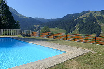 A swimming pool surrounded by a wooden fence with mountains in the background