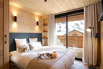 A bedroom with a sliding glass door that leads to a balcony
