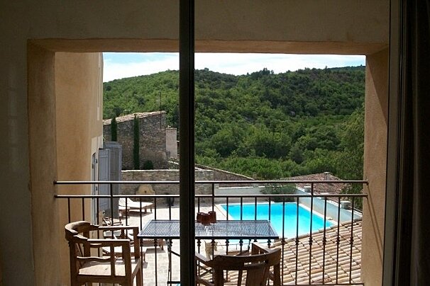 A balcony with a table and chairs overlooking a swimming pool