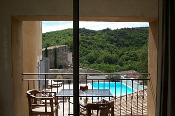 A balcony with a table and chairs overlooking a swimming pool