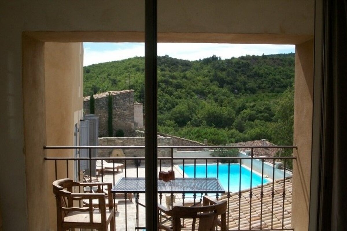 A balcony with a table and chairs overlooking a swimming pool