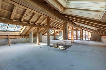 An empty attic with wooden beams and windows