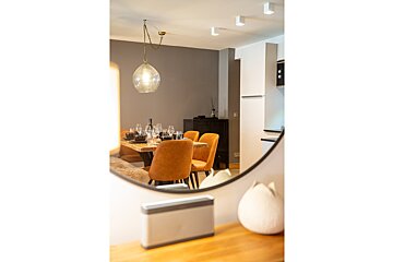 A dining room table and chairs are reflected in a mirror