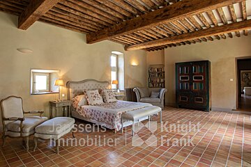 A bedroom with a bed and chairs and a sign that says janssens immobilier