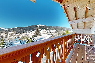 A wooden balcony with a view of snowy mountains
