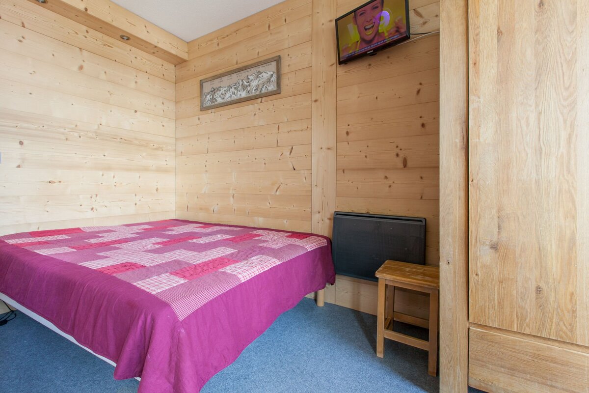 A bedroom with a bed and a television on the wall