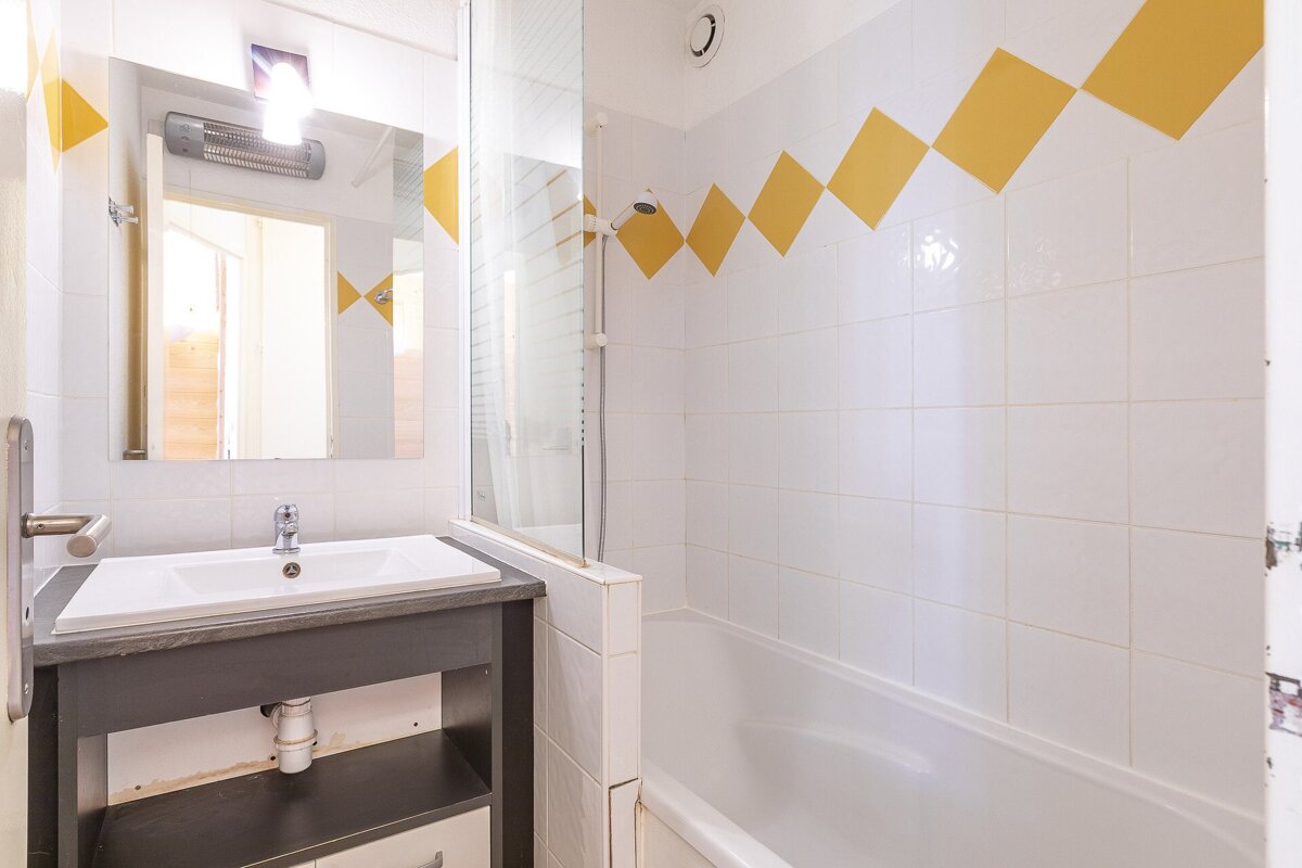 A bathroom with white tiles and yellow squares on the wall