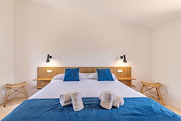 A bed with a blue blanket and blue pillows