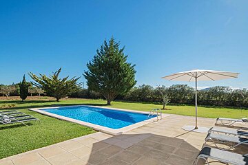 A table and chairs on a patio with a pool in the background