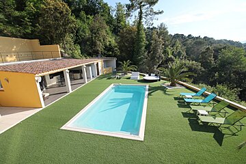 A large swimming pool surrounded by chairs and a yellow building